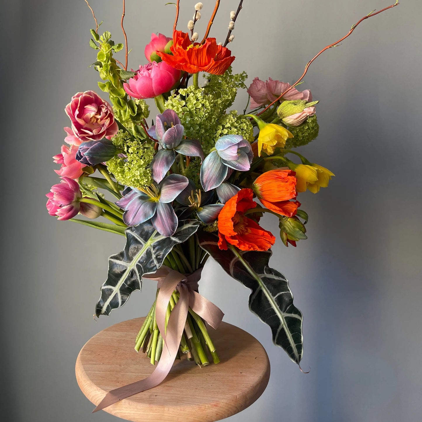 a composition from viburnum, poppy, peony, and oink and blue tulips