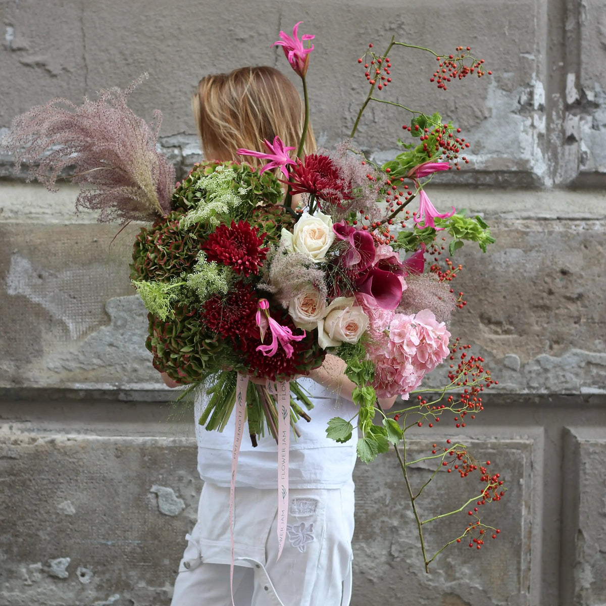 A woman holding a bouquet made with pink and green flowers