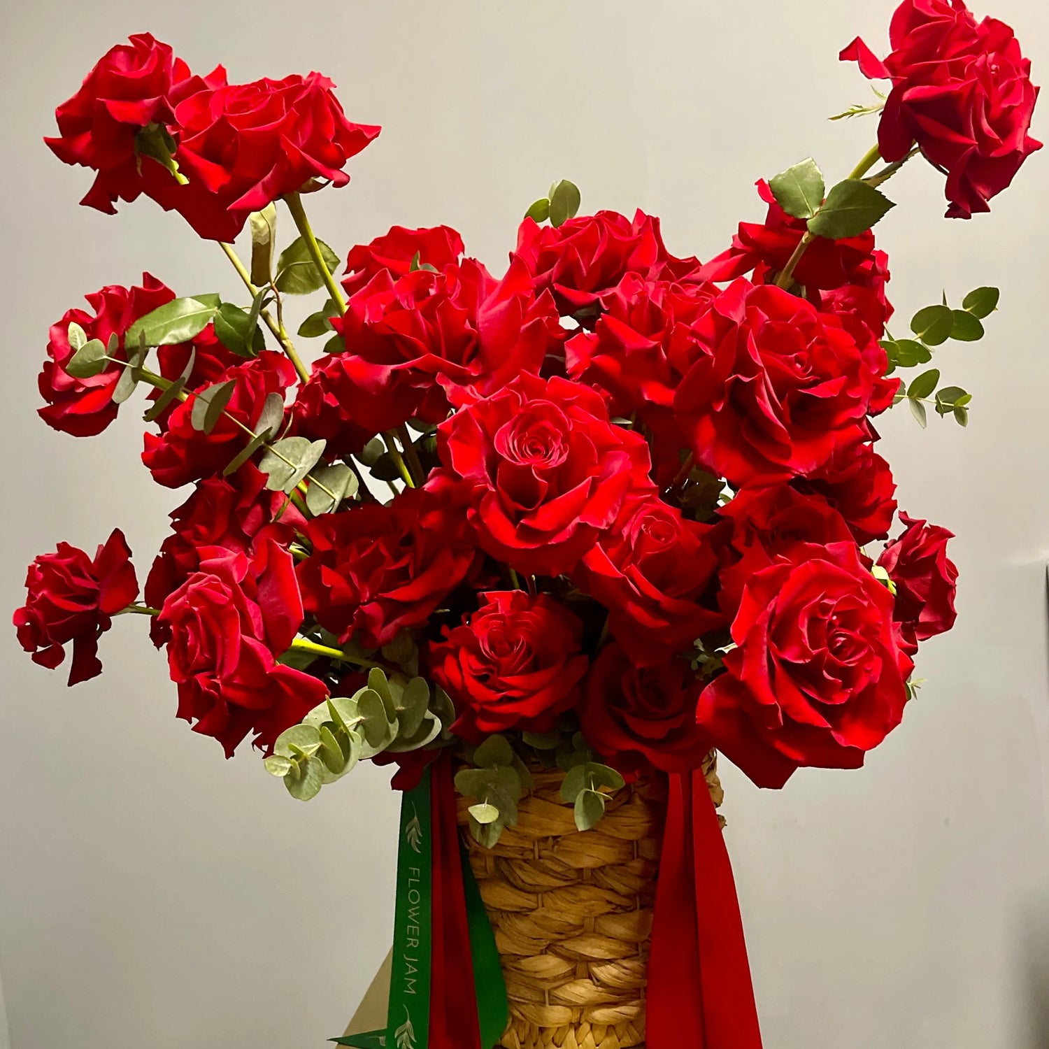 Bouquet of red roses in basket with ribbons 