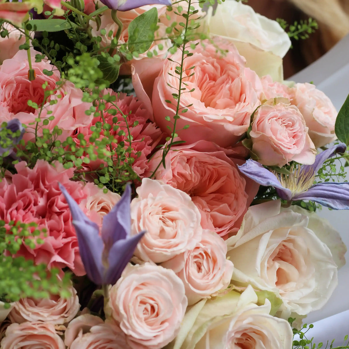 A close up on pink white and spray roses with some goodies, climatis and dianthus.