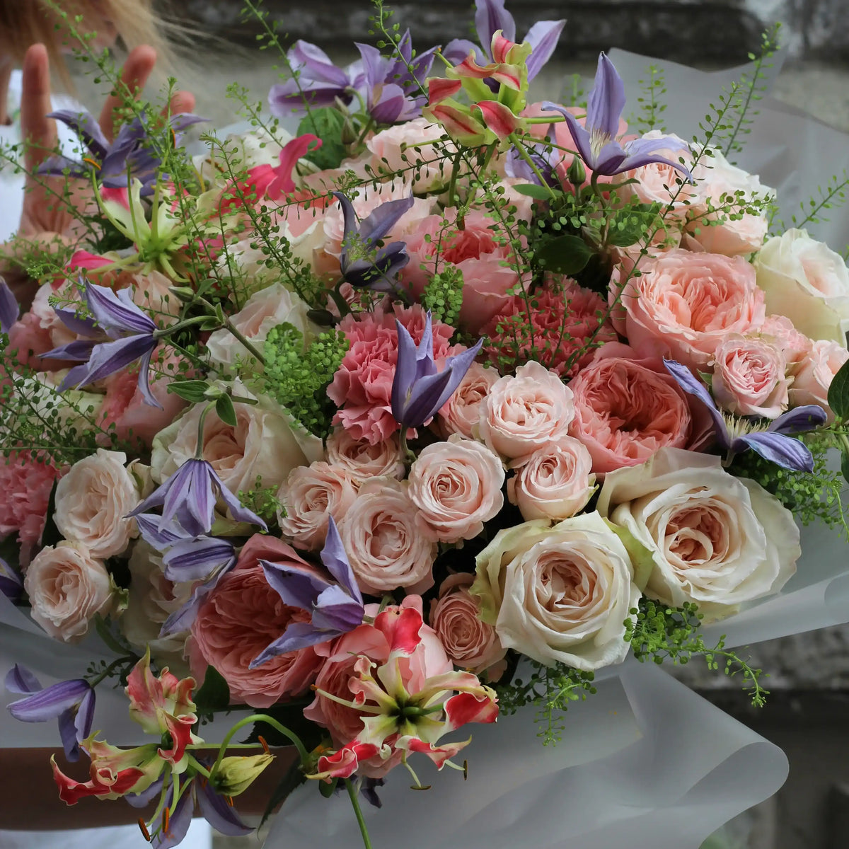 A close up on the bouquet with pink and white roses, climatis and gloriosa.
