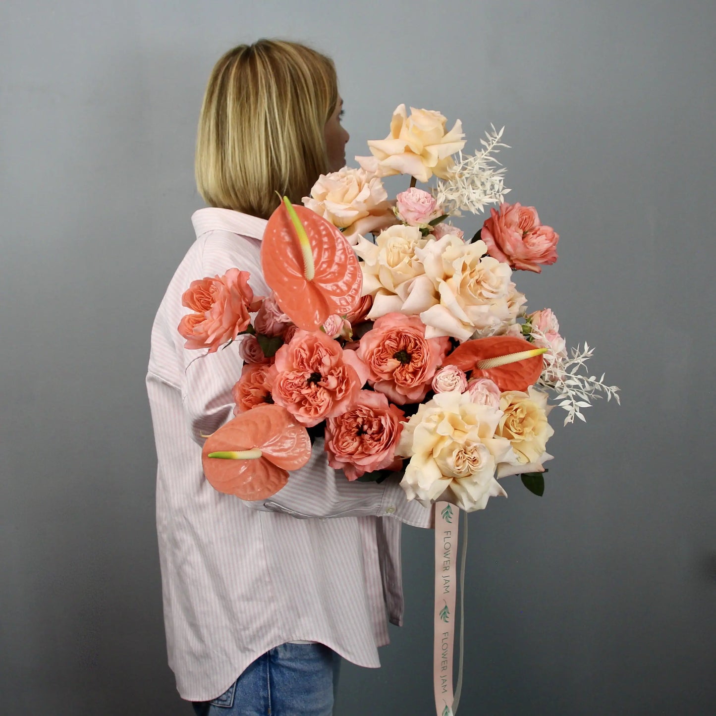 woman holding a big bouquet of orange, pink, peach and yellow flowers