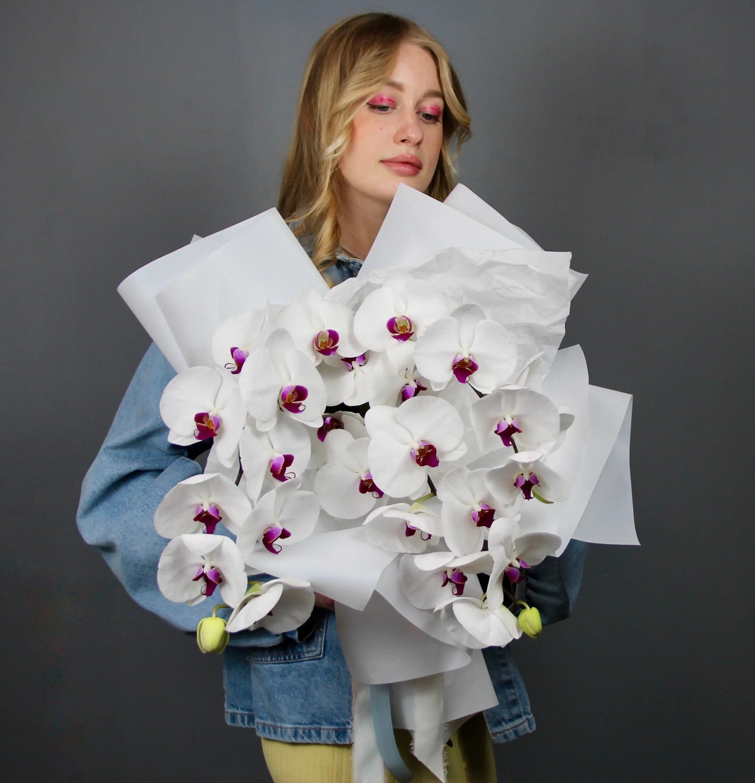 woman with pink eyeshadow holding a bouquet of white flowers