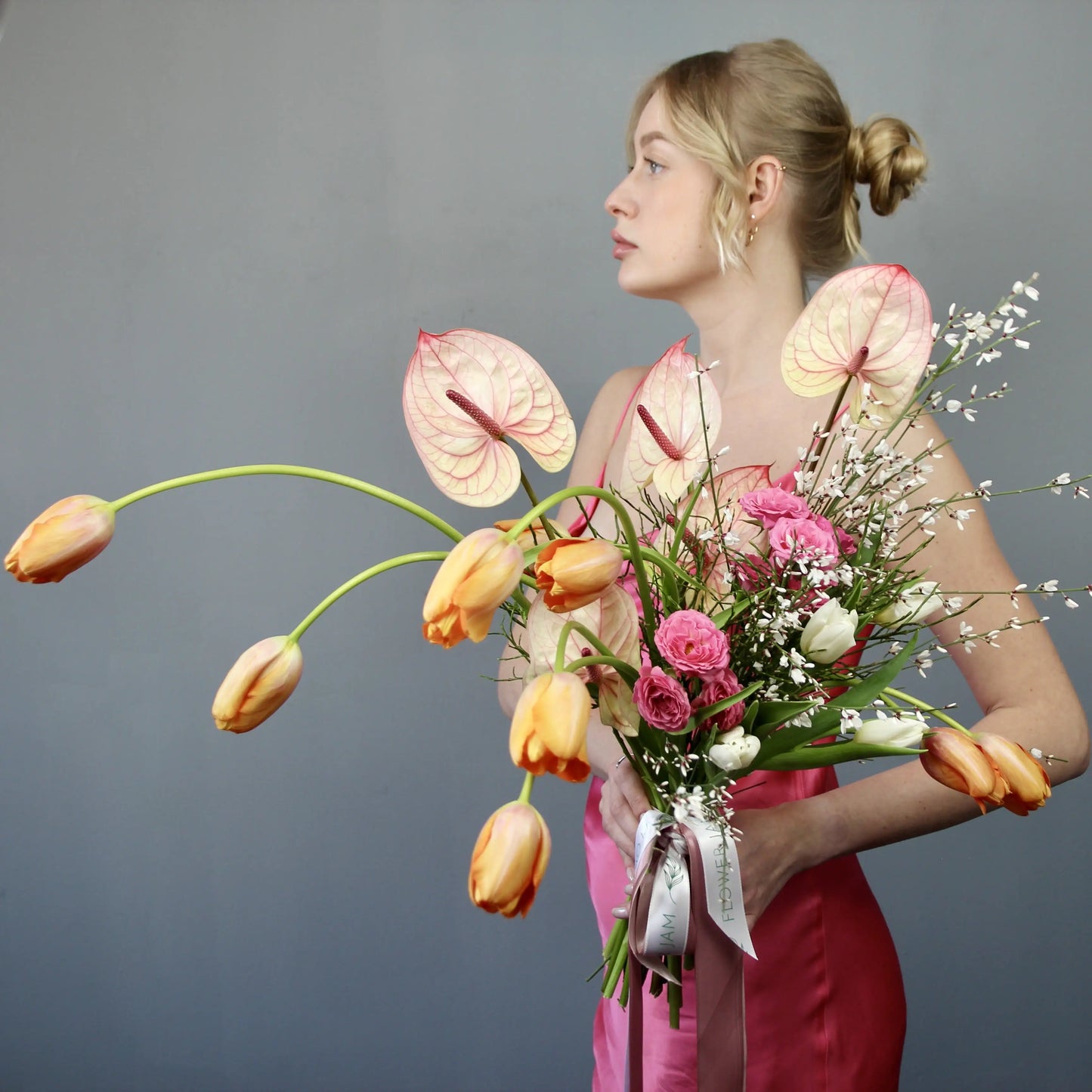woman in a pink dress with bouquet of tulips and anthurium