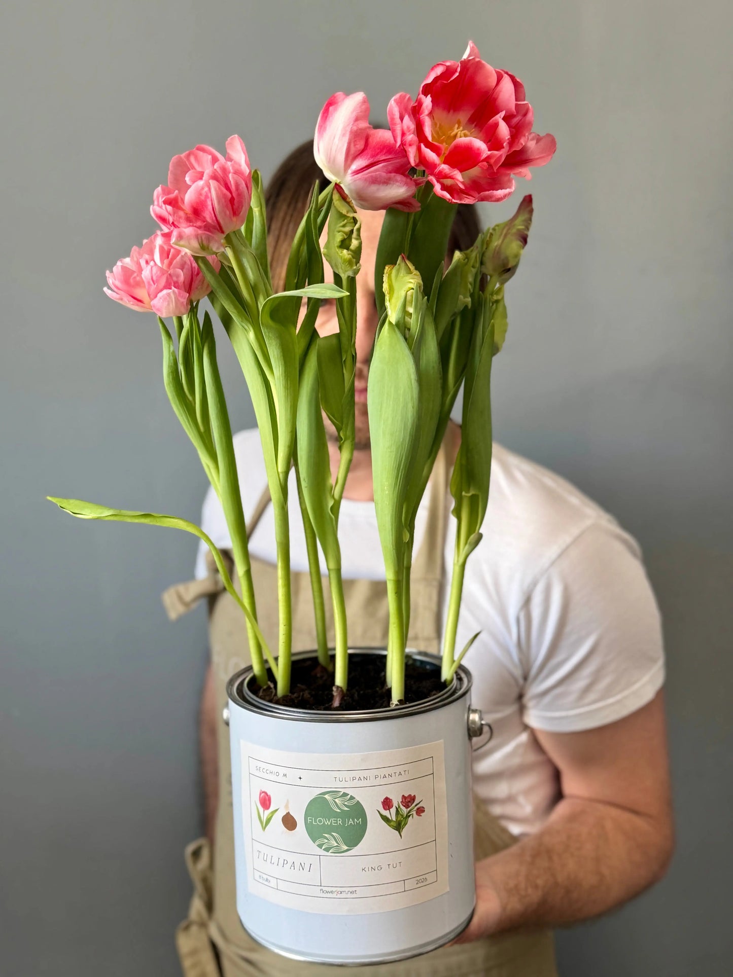 Man holding pink tulips in a repurposed paint can as a flower pot