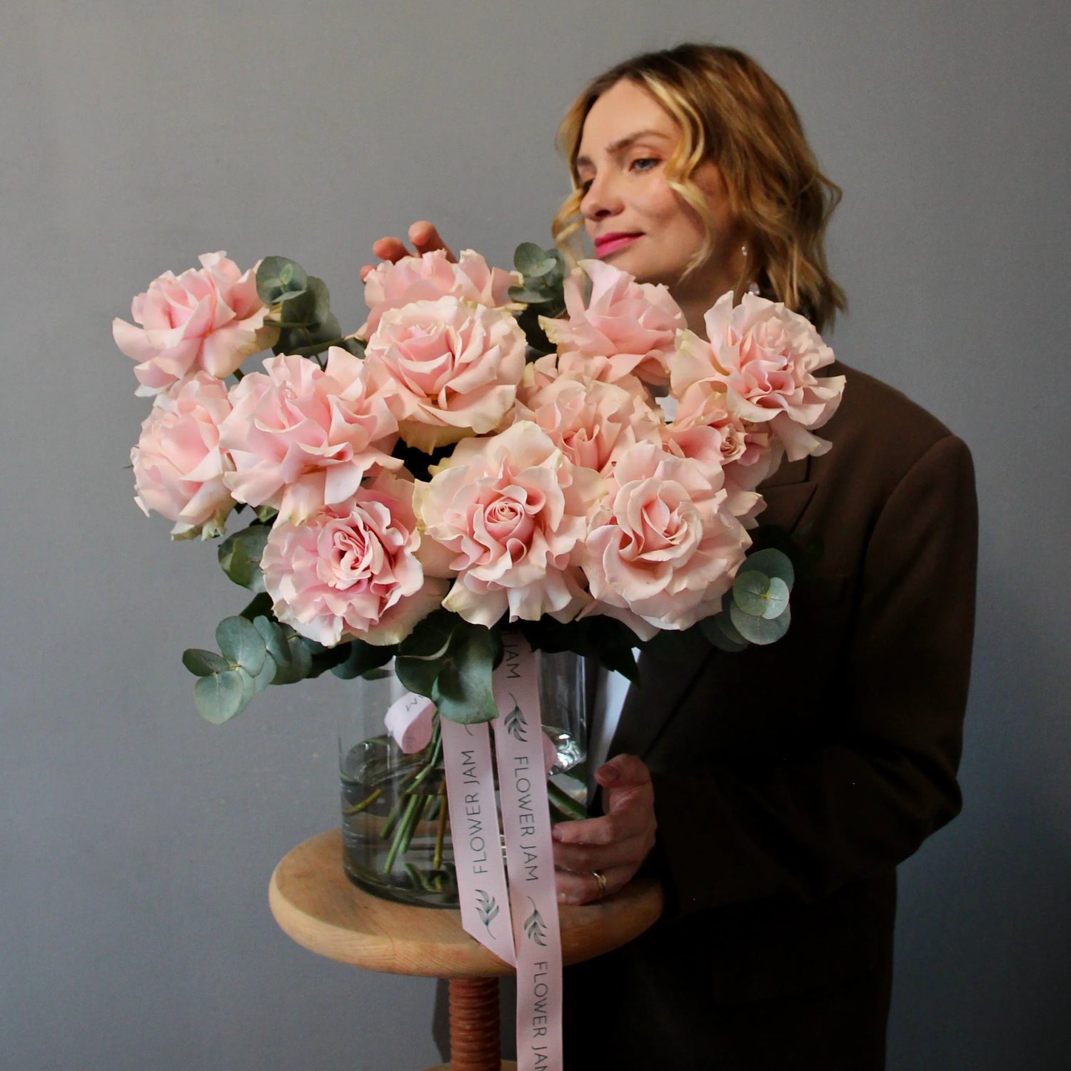 Woman holding a bouquet of pink flowers with a gray background