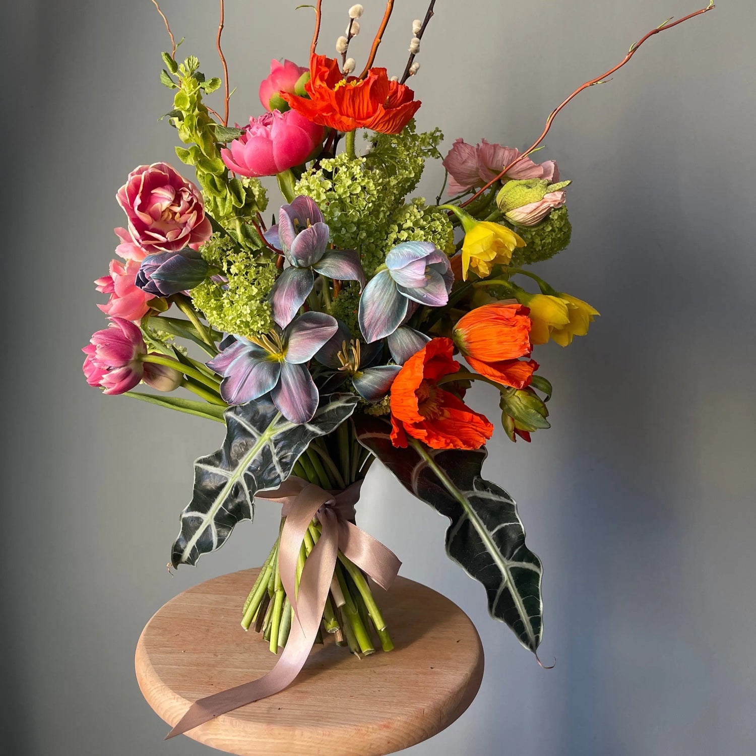 a composition from viburnum, poppy, peony, and oink and blue tulips